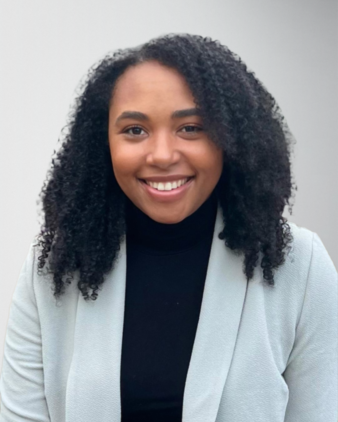 Young woman in a black turtleneck and blazer, smiling for Serengeti Wellness support team profile.