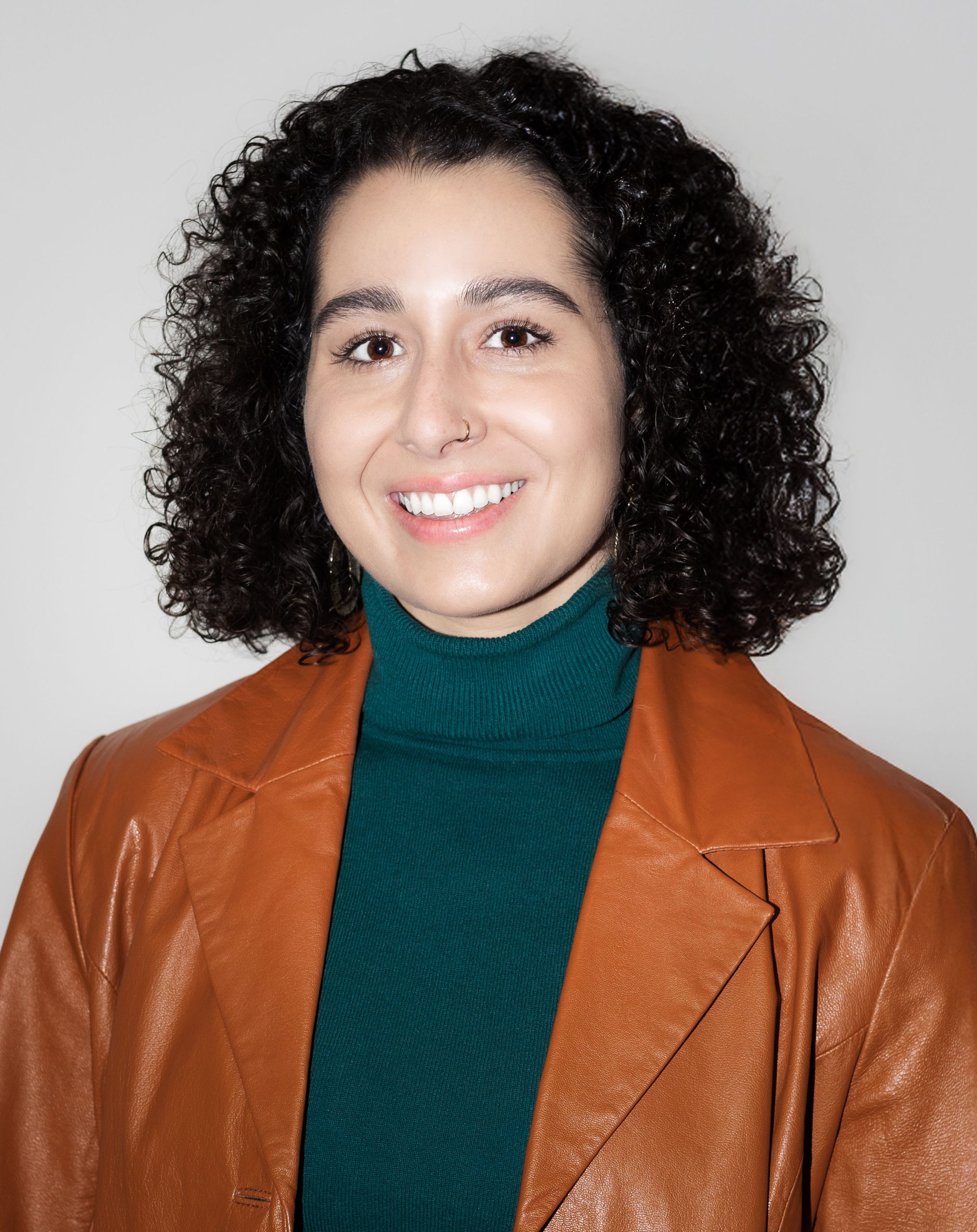 Smiling woman in brown leather jacket, representing Serengeti Wellness mental health services for BIPOC.