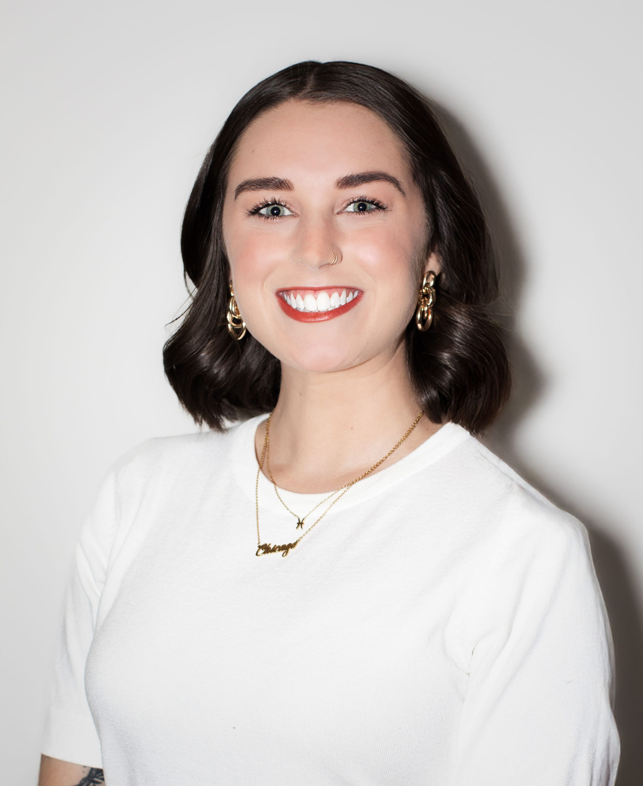 Smiling woman with wavy hair in white top, representing Serengeti Wellness for BIPOC therapy.