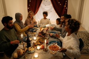 Group of diverse individuals gathered around a festive table, sharing a meal and celebrating together, representing community and connection during the holiday season.
