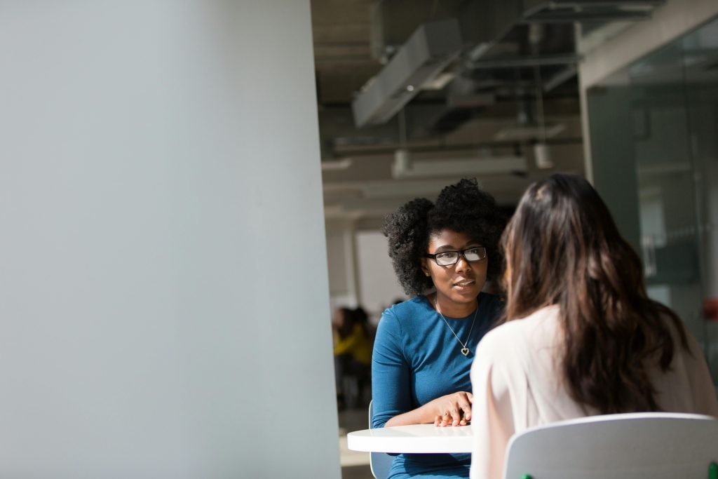 Two women in a bright workspace discussing culturally competent mental health therapy at Serengeti Wellness.
