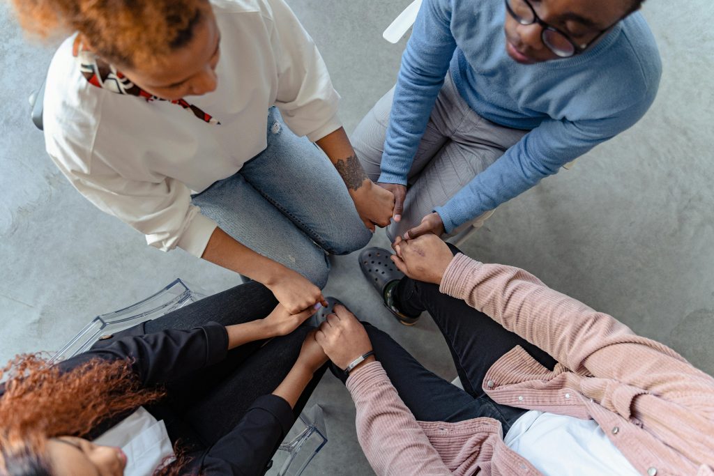 Group therapy participants holding hands in a supportive circle, emphasizing connection and shared healing experiences at Serengeti Wellness.